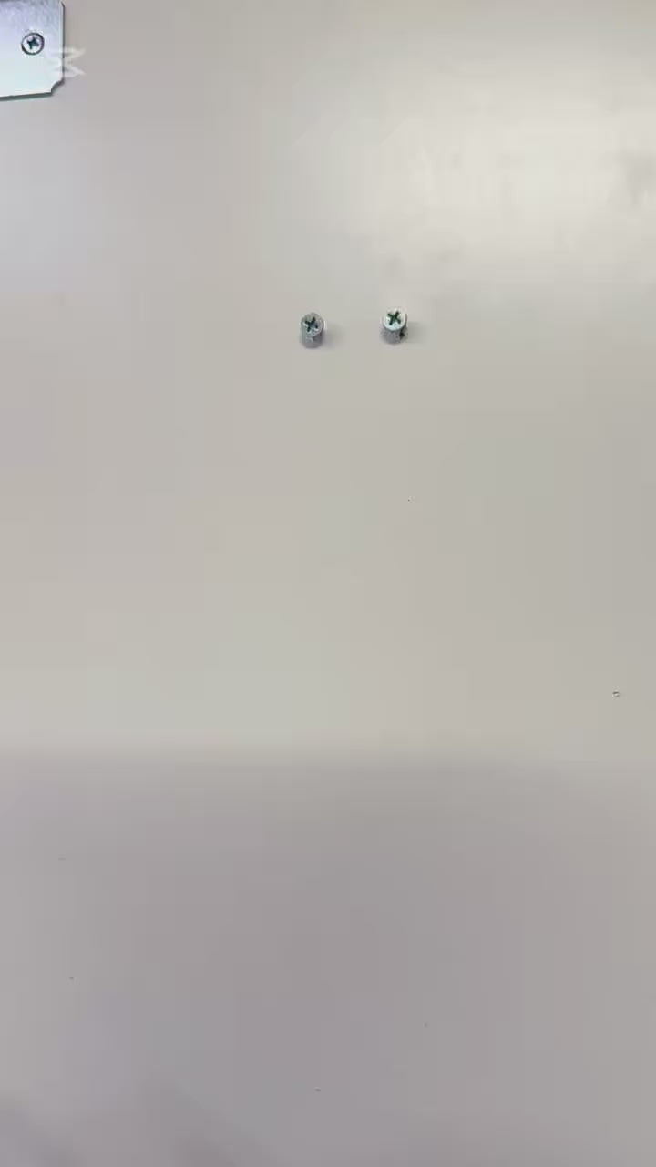 Mounted metal screws on a wall for Infant Optics Baby Monitor Wall Mount installation.